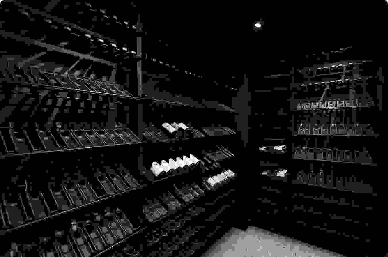 La cave à vin au sous-sol a été pensé de manière à exposer un maximum de bouteilles. L’ambiance sombre ponctuée d’éclairage artificiel permet de mettre en valeur les bouteilles.